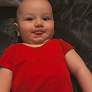 Jaxson is registered to the contest to win money with this photo: baby, infant, tongue_out, red_clothing, onesie, lying_down, cheeky, cute, skin, head, face, eyes, mouth, expression, child, person, indoors, fabric, soft, playful