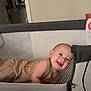 Jaxson is registered to the contest to win money with this photo: baby, infant, playpen, smile, happy, indoor, child, mesh, crib, pattern, clothing, room, floor, furniture, head, skin, arm, person, babywear, expression