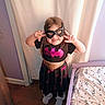 Ashley is registered to the contest to win money with this photo: child, costume, batgirl, mask, smiling, posing, bed, bedroom, bedding, cartoon, purple, black_dress, wood_floor, curtain, happy, indoors, person, playful, sock, fun