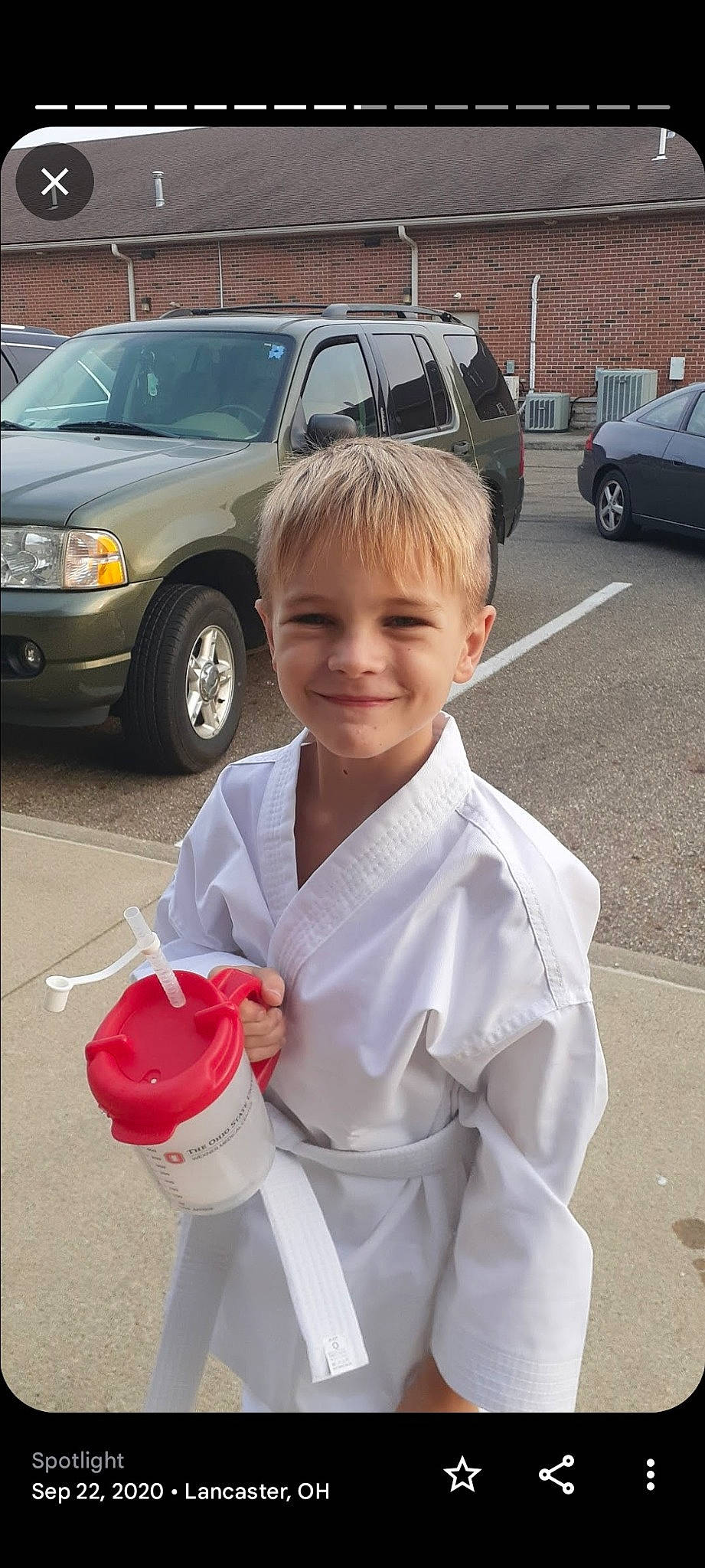 Lucas is registered to the contest to win money with this photo: asphalt, automotive_design, automotive_exterior, automotive_lighting, automotive_tire, car, fender, hood, joy, land_vehicle, motor_vehicle, parking, person, sleeve, smile, snapshot, tire, toddler, vehicle, vehicle_door