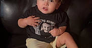 Jesus joined the competition — help win amazing prizes! toddler, child, sitting, couch, leather, portrait, curly_hair, wide_eyed, surprised, black_shirt, shorts, sneakers, neon_shoes, clothing, indoors, furniture, photograph, memorial_shirt, casual, portrait_photography