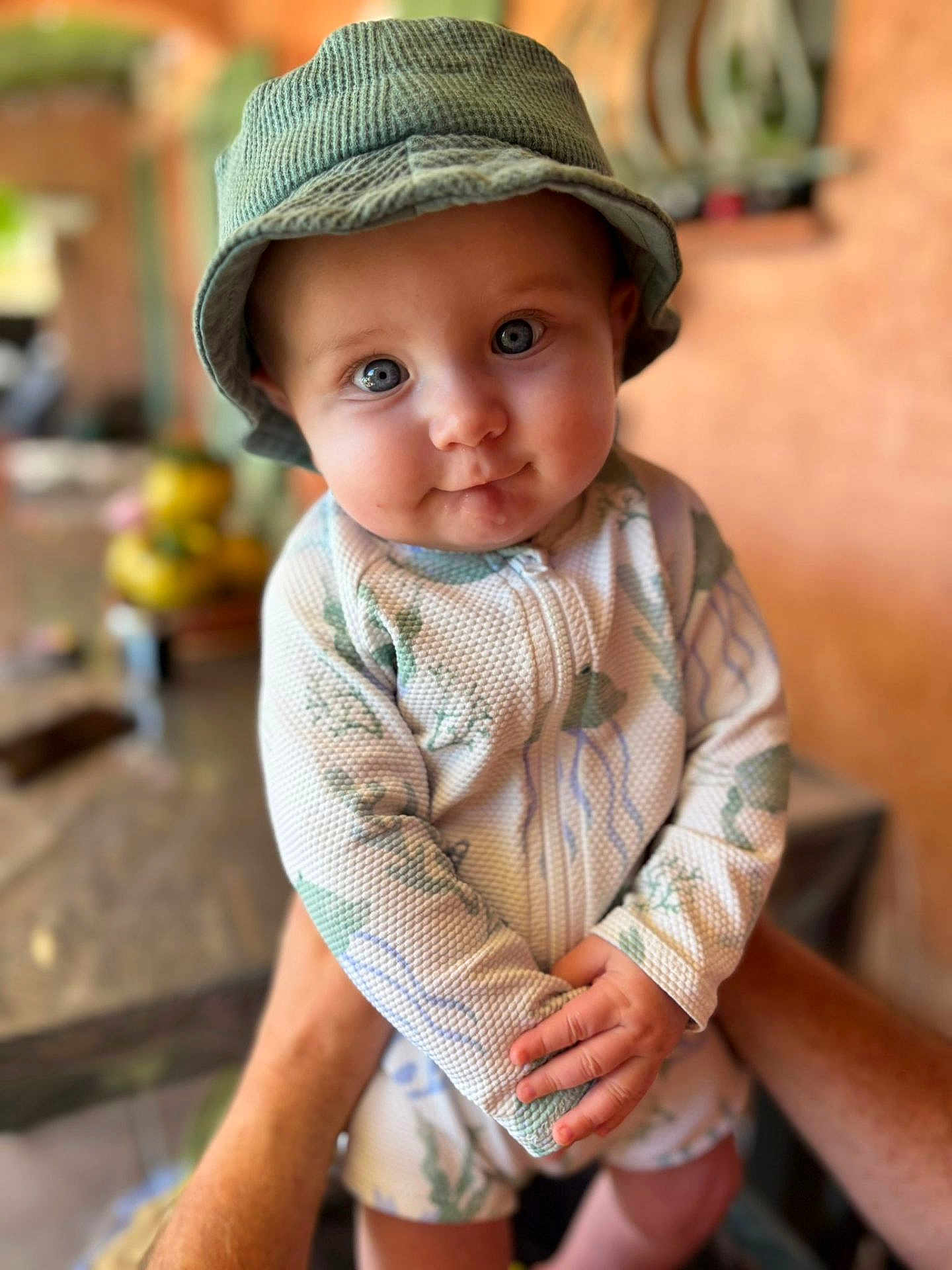 Ezio participe au concours pour gagner de l'argent avec cette photo : baby, child, blue_eyes, bucket_hat, onesie, cute, smile, hands, portrait, indoor, person, soft_focus, patterned_clothing, infant, human, face, closeup, holding, adorable, expression