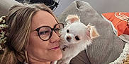 Polly joined the competition — help win amazing prizes! woman, glasses, dog, small_dog, white_dog, couch, blanket, pillow, indoor, casual, smile, affection, pet, shoulder, relaxation, home, cozy, blonde_hair, eyewear, portrait