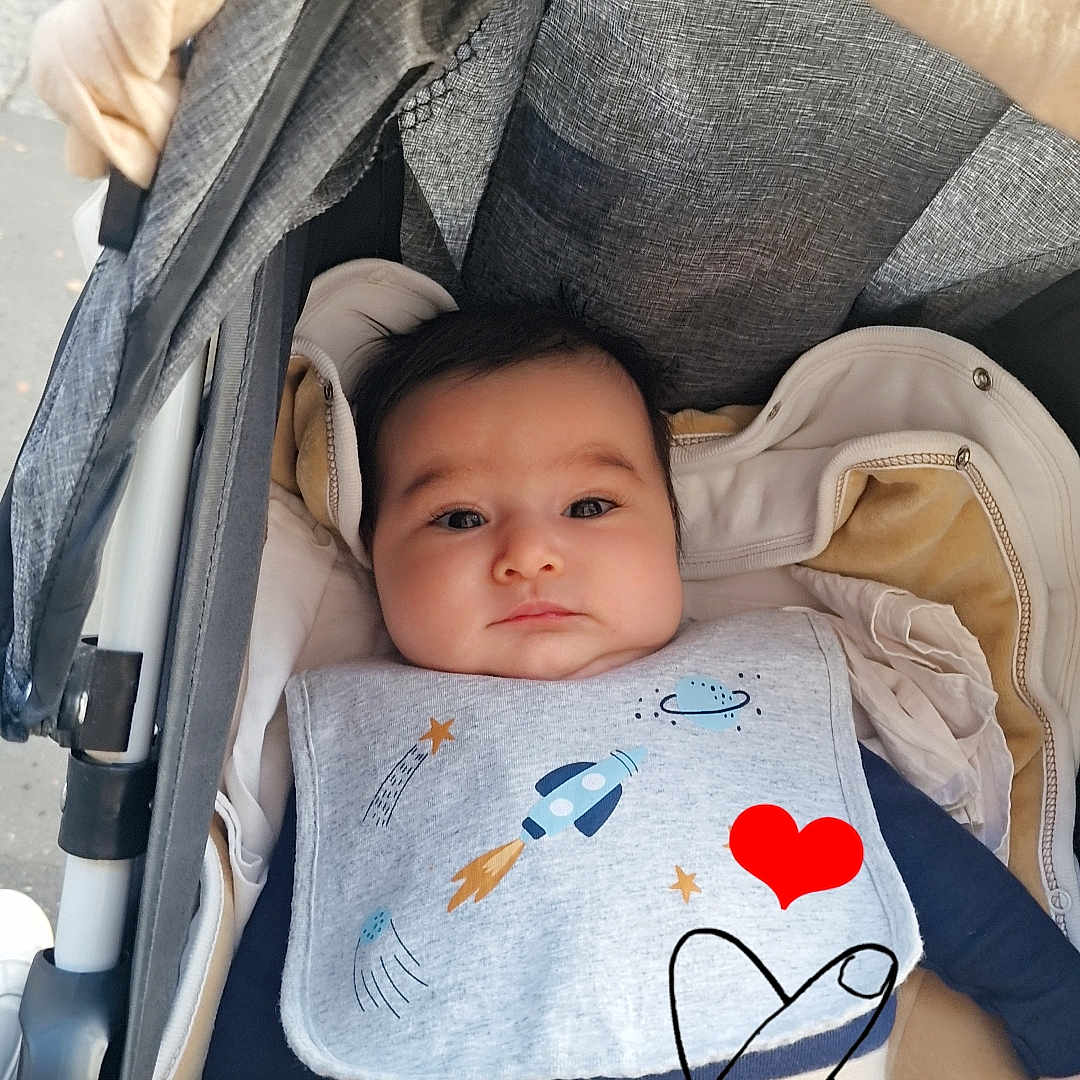 Gaya participe au concours pour gagner de l'argent avec cette photo : baby, baby_clothes, bib, blanket, child, clothing, comfort, cute, fabric, face, hand_drawn_overlay, heart, indoors, infant, outerwear, pacifier, person, portrait, relaxing, stroller