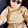 baby, child, sunglasses, beige_clothing, ribbed_fabric, infant, babybjorn, seat, relaxed, cute, portrait, indoor, fashion, comfort, young_child, face, hand, cozy, casual, wearing