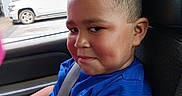 Jayden is registered to the contest to win money with this photo: child, boy, car, seatbelt, blue_shirt, curly_hair, window, vehicle, smile, face, seat, interior, casual_clothing, portrait, young, person, sitting, daylight, vehicle_interior, curious_expression