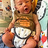 newborn, baby, infant, child, portrait, yawning, sitting, baby_seat, harness, blanket, colorful, patterned, animal_print, playroom, indoor, cozy, clothing, orange_shorts, facial_expression, photography
