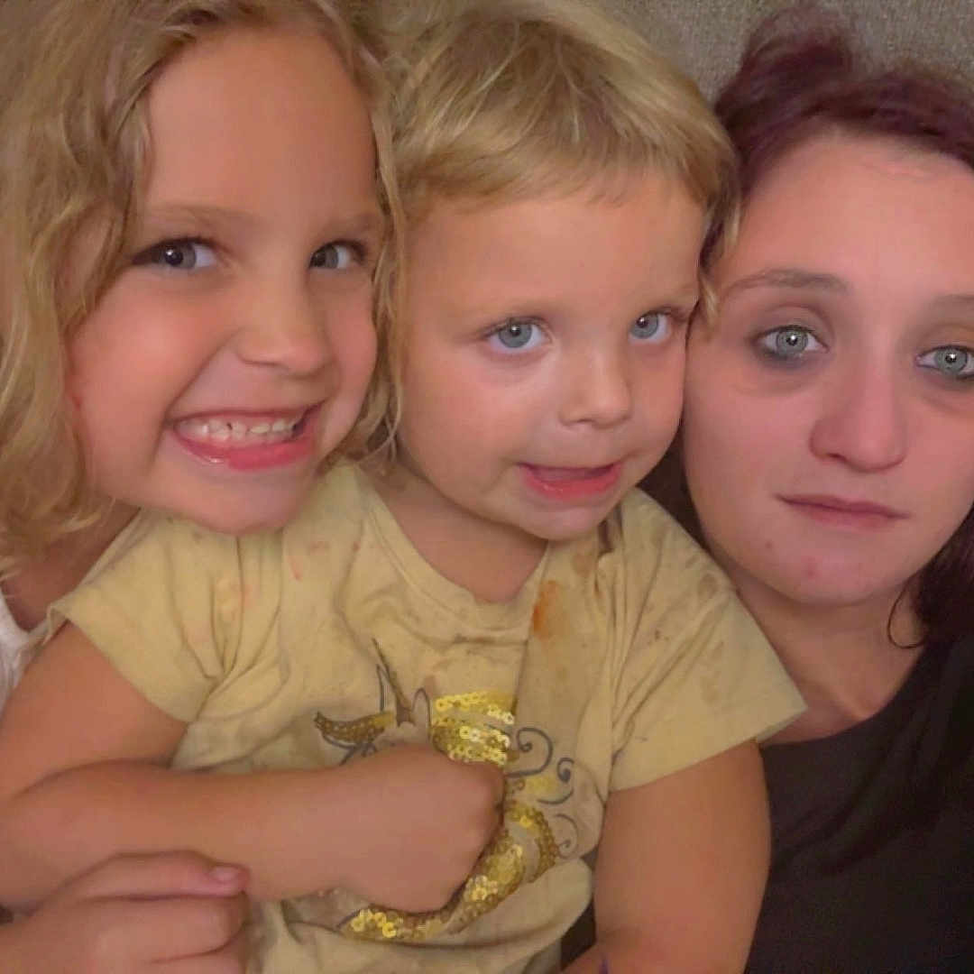 Gypsi is registered to the contest to win money with this photo: blonde_hair, blue_eyes, casual_clothing, child, children, closeup, couch, curly_hair, family, happy, home, indoor, long_hair, portrait, relaxed, short_hair, sitting, smile, tshirt, woman