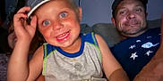 Oakley is registered to the contest to win money with this photo: child, boy, man, cap, smile, blue_eyes, couch, indoor, family, casual_clothing, portrait, happy, people, t-shirt, arm, living_room, closeup, fun, hat, face