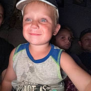 Oakley is registered to the contest to win money with this photo: child, boy, family, people, indoor, low_light, smile, cap, tank_top, couch, adult, woman, man, portrait, casual, group, seated, face, expression, home