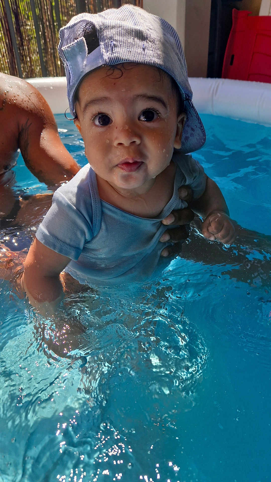 Terence participe au concours pour gagner de l'argent avec cette photo : baby, child, water, pool, cap, backwards_cap, tattoo, arm, splash, summer, outdoor, blue, shirt, skin, person, young_child, cute, fun, swimming, play