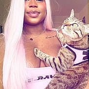 Ramsès participe au concours pour gagner de l'argent avec cette photo : person, cat, tabby_cat, pink_hair, long_hair, selfie, indoor, pet, harness, smile, necklace, tattoo, cleavage, pink_top, holding, close_up, whiskers, fur, eye_contact, cute
