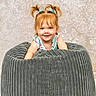 toddler, child, smile, pigtails, bean_bag, gray, cozy, cute, happy, portrait, indoor, clothing, blue, hair, face, person, texture, background, playful, young