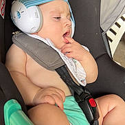 Charles participe au concours pour gagner de l'argent avec cette photo : baby, bib, black_padding, blue_stripes, car_seat, child, comfort, diaper, face, fingers, hand, headphones, indoor, infant, natural_light, noise_cancelling, safety_harness, sitting, skin, thoughtful