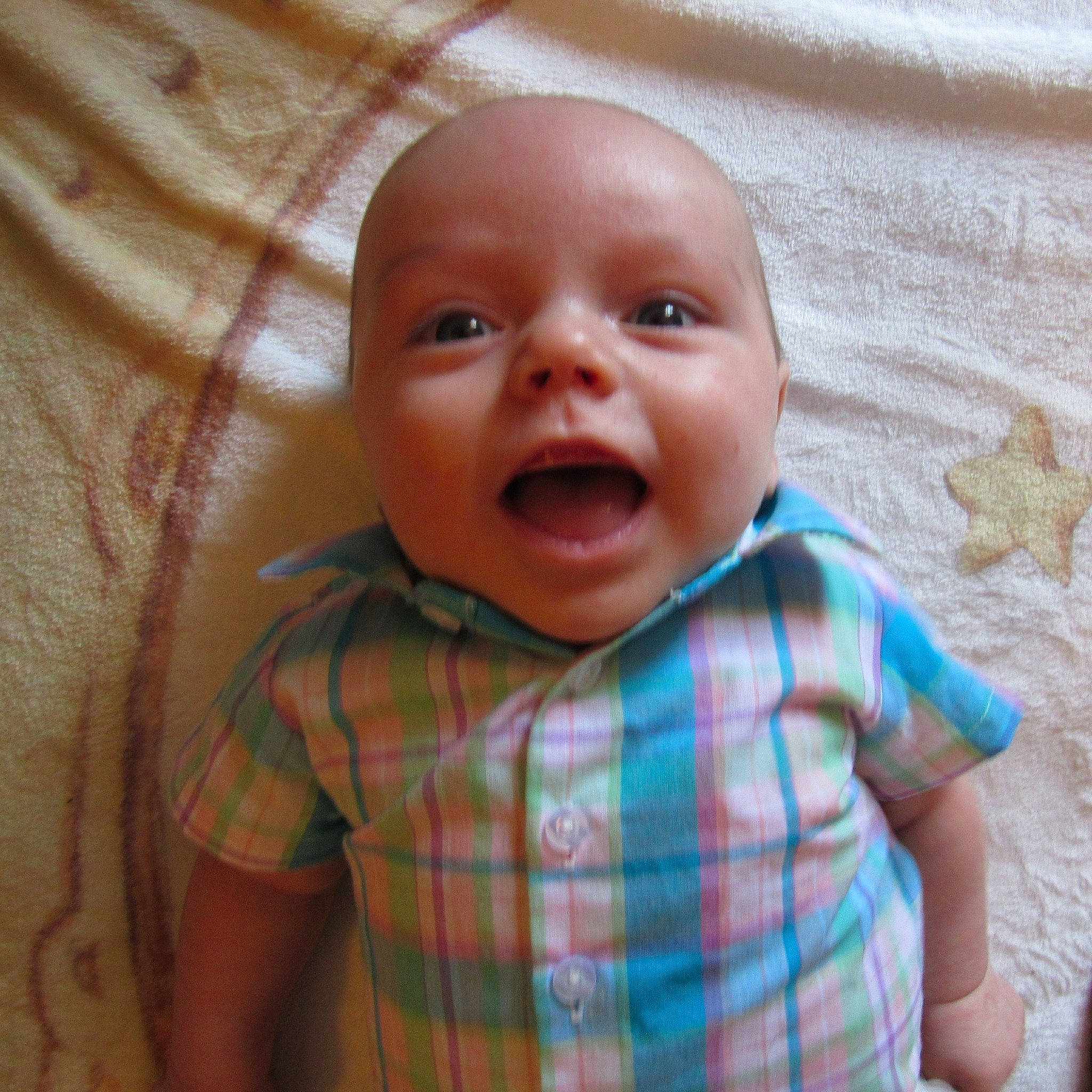Malcom is registered to the contest to win money with this photo: baby, baby_making_funny_faces, cheek, child, chin, design, eye, face, facial_expression, head, iris, lip, mouth, nose, pattern, person, plaid, skin, smile, textile