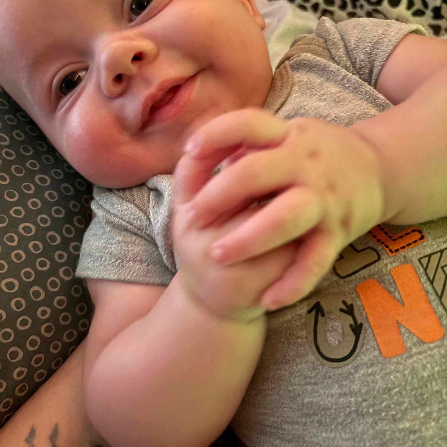 Billy G is registered to the contest to win money with this photo: accessories, arm, baby, babylaughing, bodypart, clothing, face, finger, hand, happy, head, newborn, person, photography, portrait, skin, smile, t_shirt, tattoo, wrist