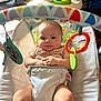 baby, infant, bouncer, toys, colorful, indoor, child, cute, smiling, seat, play, hands, face, legs, clothing, comfort, expression, closeup, happy, person