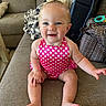 baby, child, smiling, sitting, polka_dot, pink, bow, hair_accessory, couch, indoor, happy, cute, infant, face, eyes, hand, foot, clothing, furniture, person