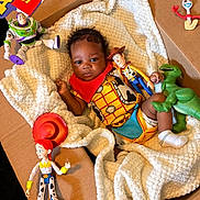 Amare is registered to the contest to win money with this photo: baby, blanket, buzz_lightyear, cardboard_box, child, colorful, costume, cute, indoor, infant, jessie, playful, plush, portrait, rex_dinosaur, slinky_dog, smiling, toy_figures, toy_story, woody_costume