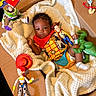 baby, blanket, buzz_lightyear, cardboard_box, child, colorful, costume, cute, indoor, infant, jessie, playful, plush, portrait, rex_dinosaur, slinky_dog, smiling, toy_figures, toy_story, woody_costume
