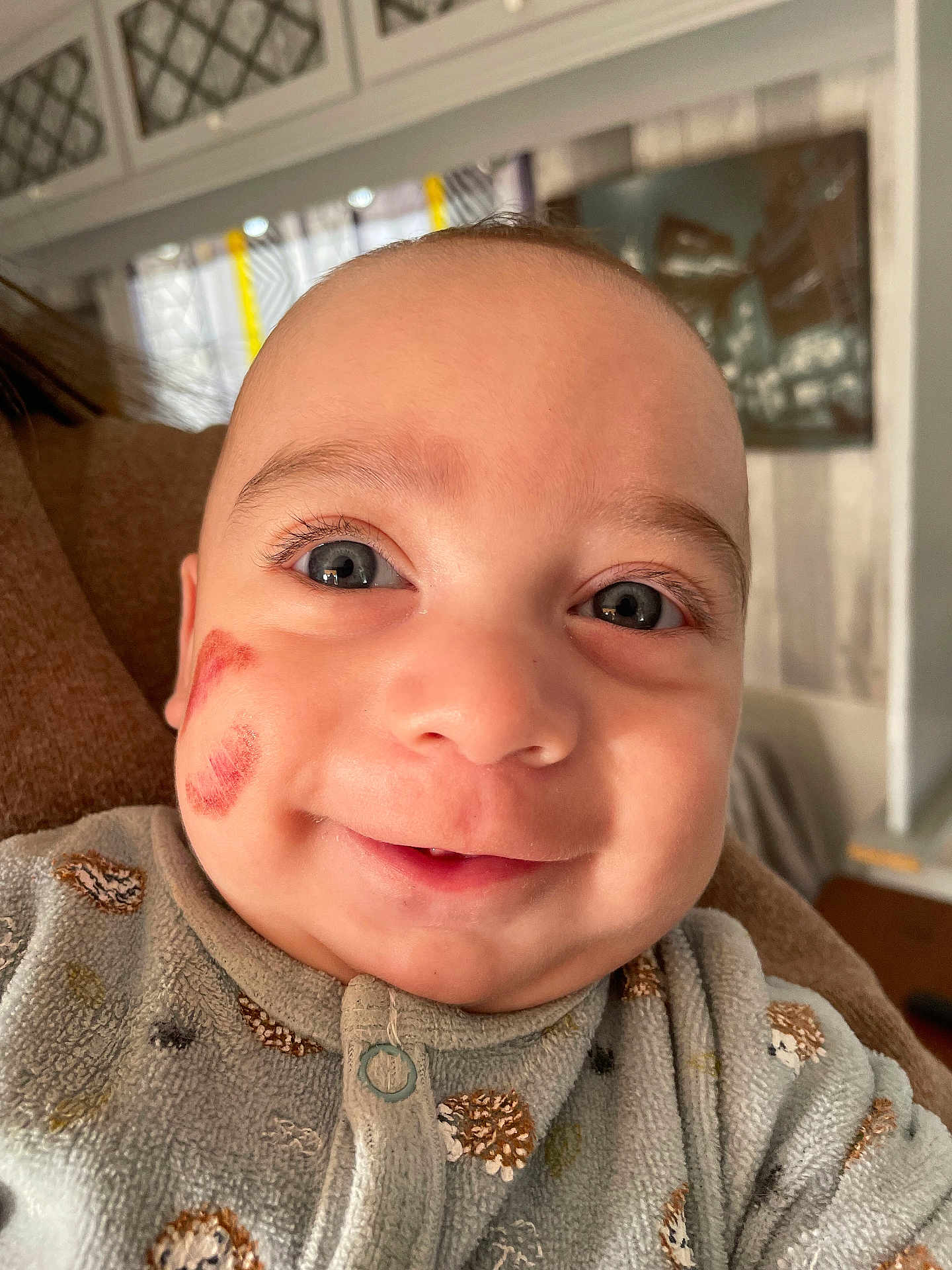 Nheylan a rejoint le concours — aidez-le/la à gagner de superbes lots ! baby, infant, close_up, portrait, smile, blue_eyes, eyelashes, kiss_mark, cheek_mark, onesie, patterned_clothing, hedgehog_print, indoor, home_interior, blanket, adult_arm, soft_lighting, joyful_expression, face, baby_clothing