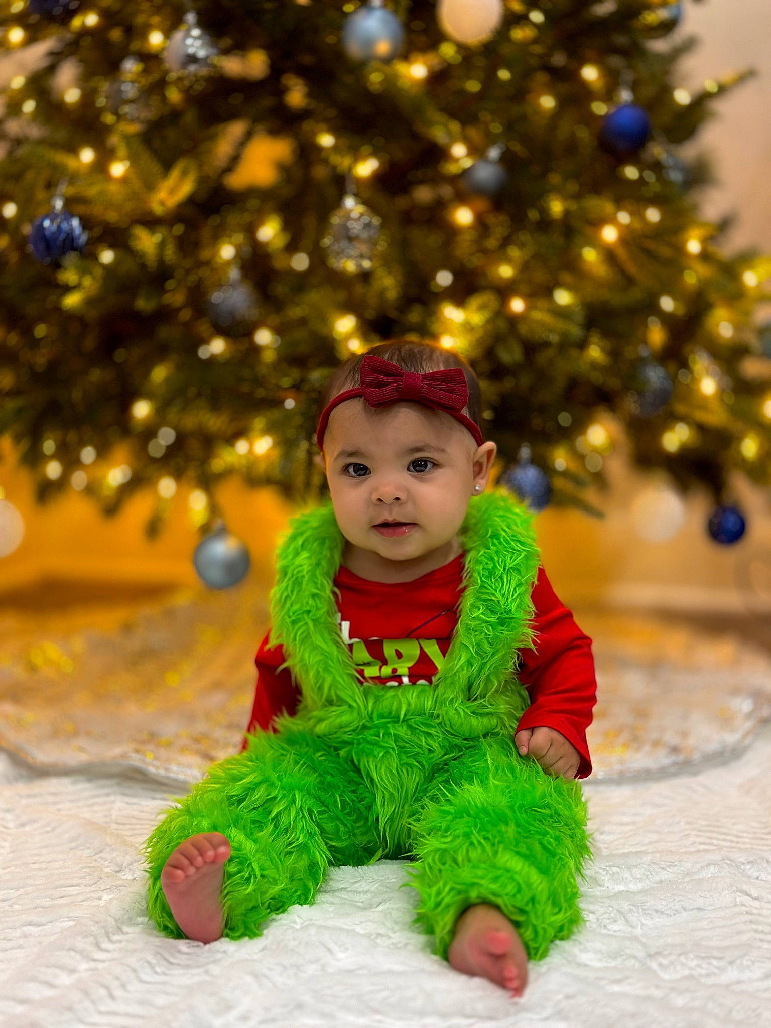 Amora is registered to the contest to win money with this photo: baby, baby_toddler_clothing, christmas, christmas_decoration, christmas_ornament, christmas_tree, dress, event, eye, fun, grass, happy, headwear, holiday, human_body, ornament, outerwear, people_in_nature, person, sleeve