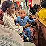 Kiondre joined the competition — help win amazing prizes! child, toddler, woman, glasses, suit, bow_tie, church, pew, people, indoor, seated, smile, formal_wear, audience, event, hairstyle, jewelry, holding, portrait, multigenerational