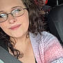 woman, child, car, seatbelt, glasses, ear_protection, knitted_sweater, curly_hair, portrait, indoor, vehicle_interior, seat, window, roadside, casual_clothing, smile, person, travel, family, daylight