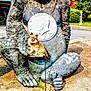 dog, statue, gorilla, coin, outdoor, sunny, concrete, leash, tree, greenery, building, chain, animal, pet, sculpture, pavement, small_dog, cute, contrast, funny