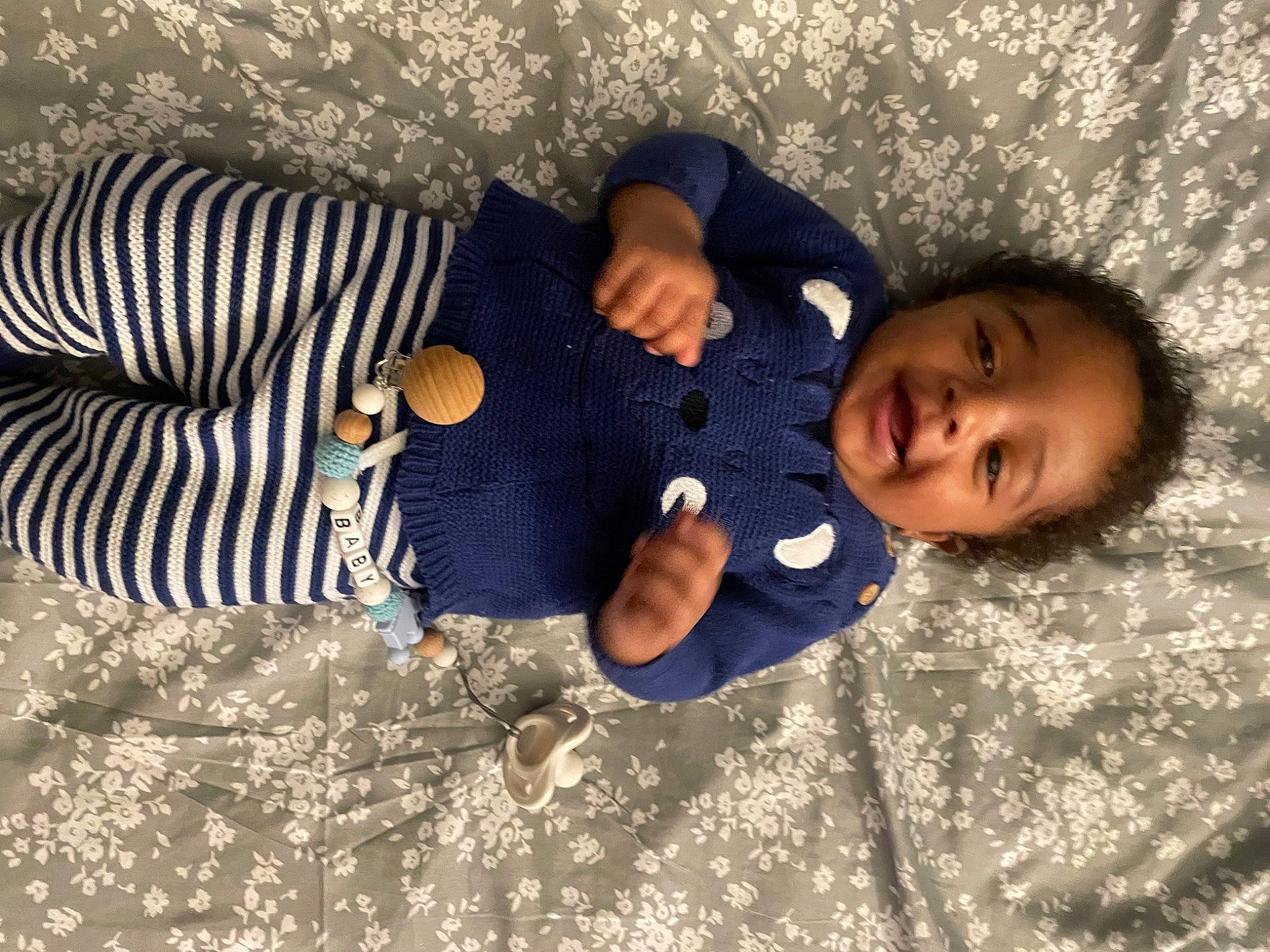 Dwight is registered to the contest to win money with this photo: baby, baby_toddler_clothing, child, comfort, cool, fun, grass, happy, human_leg, linens, pattern, people_in_nature, person, sand, sitting, soil, toddler, tree, vacation, winter