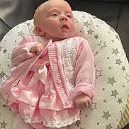 Maddie joined the competition — help win amazing prizes! baby, infant, pink_clothing, dress, knit_cardigan, cushion, stars_pattern, blue_eyes, hand, soft_fabric, cute, portrait, indoor, child, newborn, comfort, resting, small_fingers, cozy, adorable