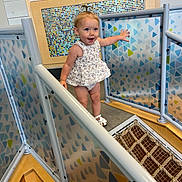 Hadleigh is registered to the contest to win money with this photo: active, child, colorful, curly_hair, dress, exploring, fun, happy, indoor, patterned_panels, person, play_area, playground, railing, rope_bridge, smiling, toddler, white_sandals, wooden_floor, young_child