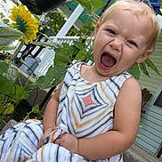 Hadleigh joined the competition — help win amazing prizes! toddler, child, girl, blue_bow, dress, patterned_dress, outdoor, garden, plants, sunflower, porch, concrete, greenery, expression, yawn, scream, summer, nature, happy, casual