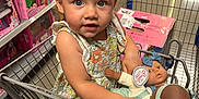 Hadleigh joined the competition — help win amazing prizes! toddler, child, shopping_cart, doll, toy_store, aisle, toys, floral_dress, blue_eyes, shopping, plastic, retail, store_shelves, floor, person, holding, cute, indoor, playful, curious