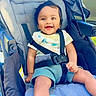 baby, stroller, smiling, child, happy, seatbelt, blue_blanket, outdoor, infant, clothing, child_safety, cute, portrait, baby_clothes, seated, sunlight, young_child, baby_girl, comfort, casual