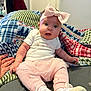 baby, child, infant, tutu, headband, pink_clothing, hand_holding, blanket, patterned_blanket, sitting, footwear, white_shoes, indoor, person, cute, expression, face, wide_eyes, soft_lighting, home