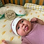 Karlina M Yokley is registered to the contest to win money with this photo: baby, infant, crib, hat, clothing, tongue, cute, wooden_sign, patterned_sheet, bed, sleeping_area, child, newborn, face, expression, person, lying_down, cute_outfit, nursery, playful