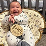 baby, infant, smile, happy, onesie, chair, patterned, clothing, hands, feet, indoor, carpet, crib, wood, fabric, cute, child, person, young, four_months