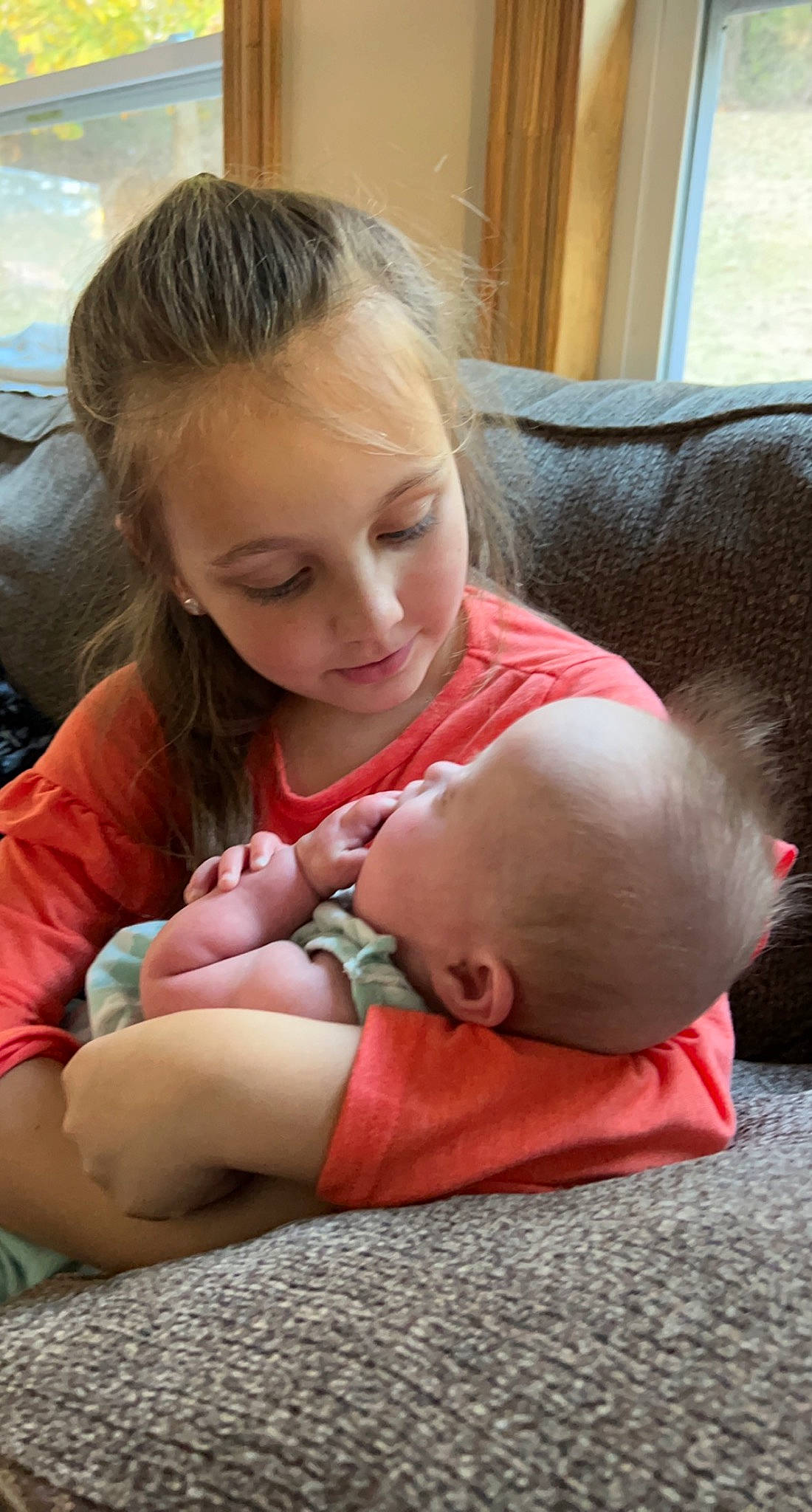 Emerie is registered to the contest to win money with this photo: baby, barefoot, child, comfort, couch, face, flooring, foot, fun, happy, head, human_leg, joint, knee, lap, person, room, sitting, skin, thigh