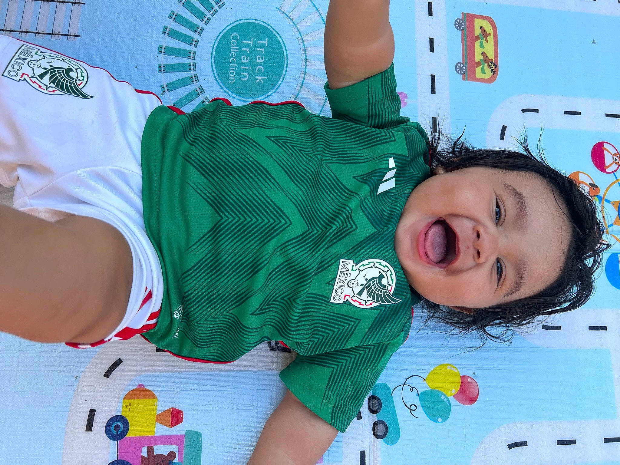 Tre is registered to the contest to win money with this photo: baby, baby_toddler_clothing, carmine, child, event, fun, green, happy, pattern, person, product, red, sleeve, smile, sock, sportswear, t_shirt, textile, thigh, toddler