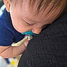 baby, pacifier, sleeping, close_up, blue_clothing, face, child, infant, peaceful, resting, skin, hair, ear, eyelashes, person, soft_lighting, fabric, comfort, cute, portrait
