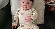Leané is registered to the contest to win money with this photo: baby, blanket, child, comfort, couch, cozy, cute, flower, headband, heart_pattern, home, indoor, infant, looking_at_camera, pajamas, person, pillow, relaxed, seated, soft_lighting