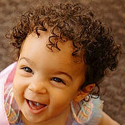 Kya is registered to the contest to win money with this photo: child, toddler, curly_hair, smiling, happy, face, portrait, cute, baby, eyes, clothing, pastel_colors, indoors, close_up, joyful, young_child, ruffles, skin, person, background