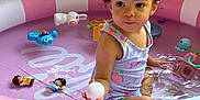Kya is registered to the contest to win money with this photo: toddler, child, inflatable_pool, pink, white, water, toy, ball, curly_hair, outdoor, summer, play, cute, skin, sleeveless, expression, person, small, fun, daylight