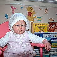 Indigo joined the competition — help win amazing prizes! child, baby, toddler, pink_chair, knitted_hat, book_shelf, books, winnie_the_pooh, piglet, tigger, wall_decals, nursery, grumpy_expression, portrait, hand, arm, white_clothing, indoor, seat, picture_books