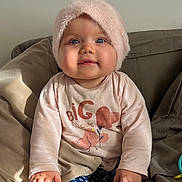 Edline a rejoint le concours — aidez-le/la à gagner de superbes lots ! baby, child, hat, pink, shirt, blue_eyes, sofa, pillows, toy, hands, sitting, indoor, cute, infant, face, clothing, cozy, expression, furniture, young_child
