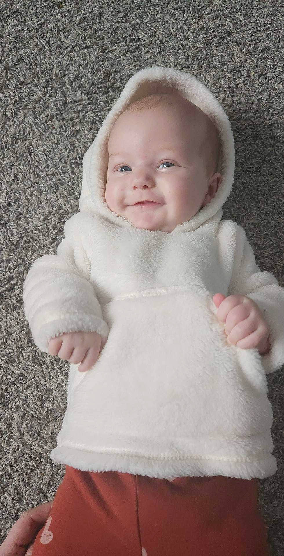 Oaklee is registered to the contest to win money with this photo: baby, baby_toddler_clothing, cheek, collar, comfort, eye, fur, gesture, grey, happy, iris, lip, neck, nose, pattern, person, pink, skin, sleeve, smile