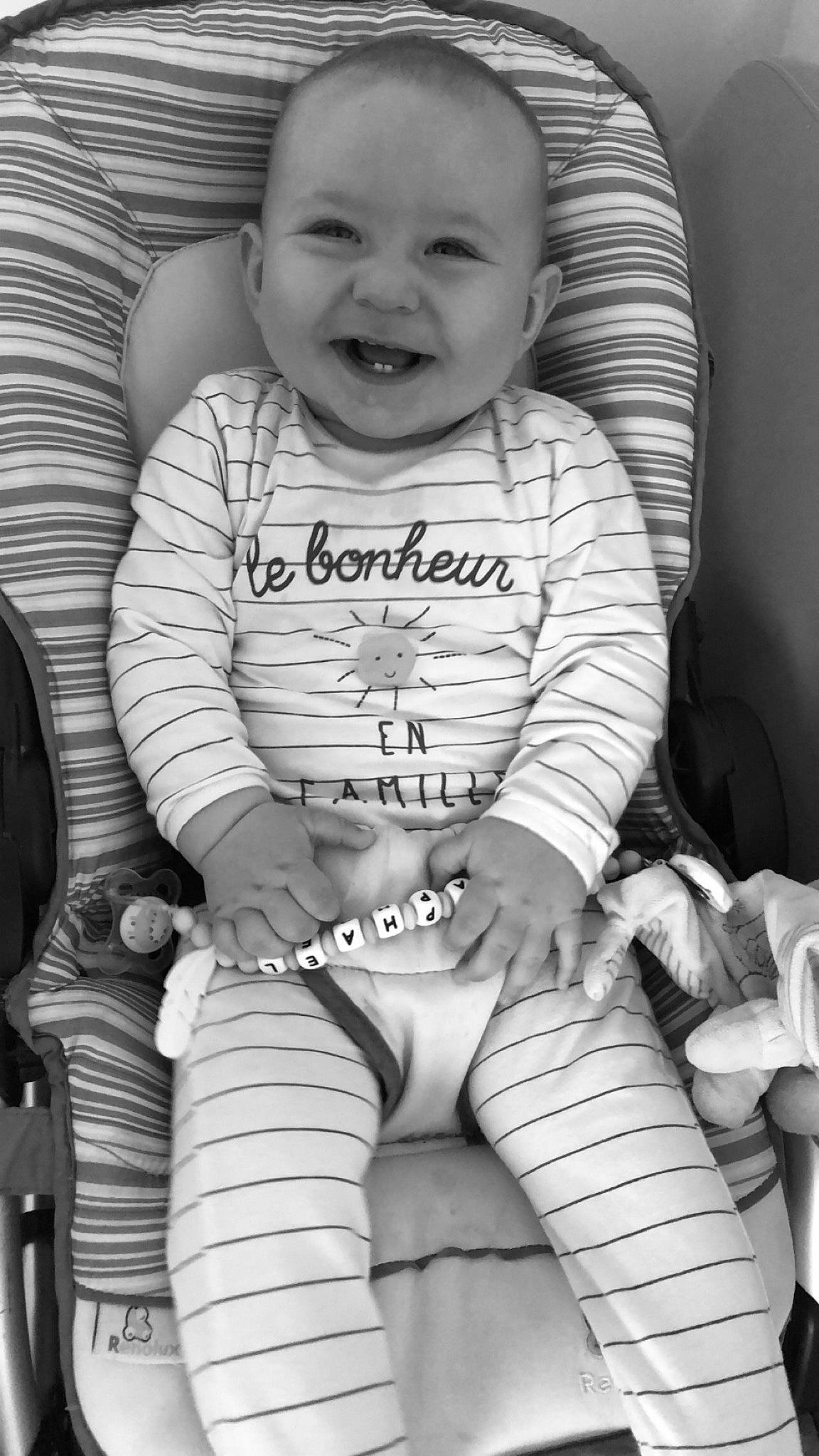 Raphaël participe au concours pour gagner de l'argent avec cette photo : baby, baby_products, baby_toddler_clothing, black_and_white, child, facial_expression, joy, monochrome, person, photography, product, sitting, smile, style, toddler, white