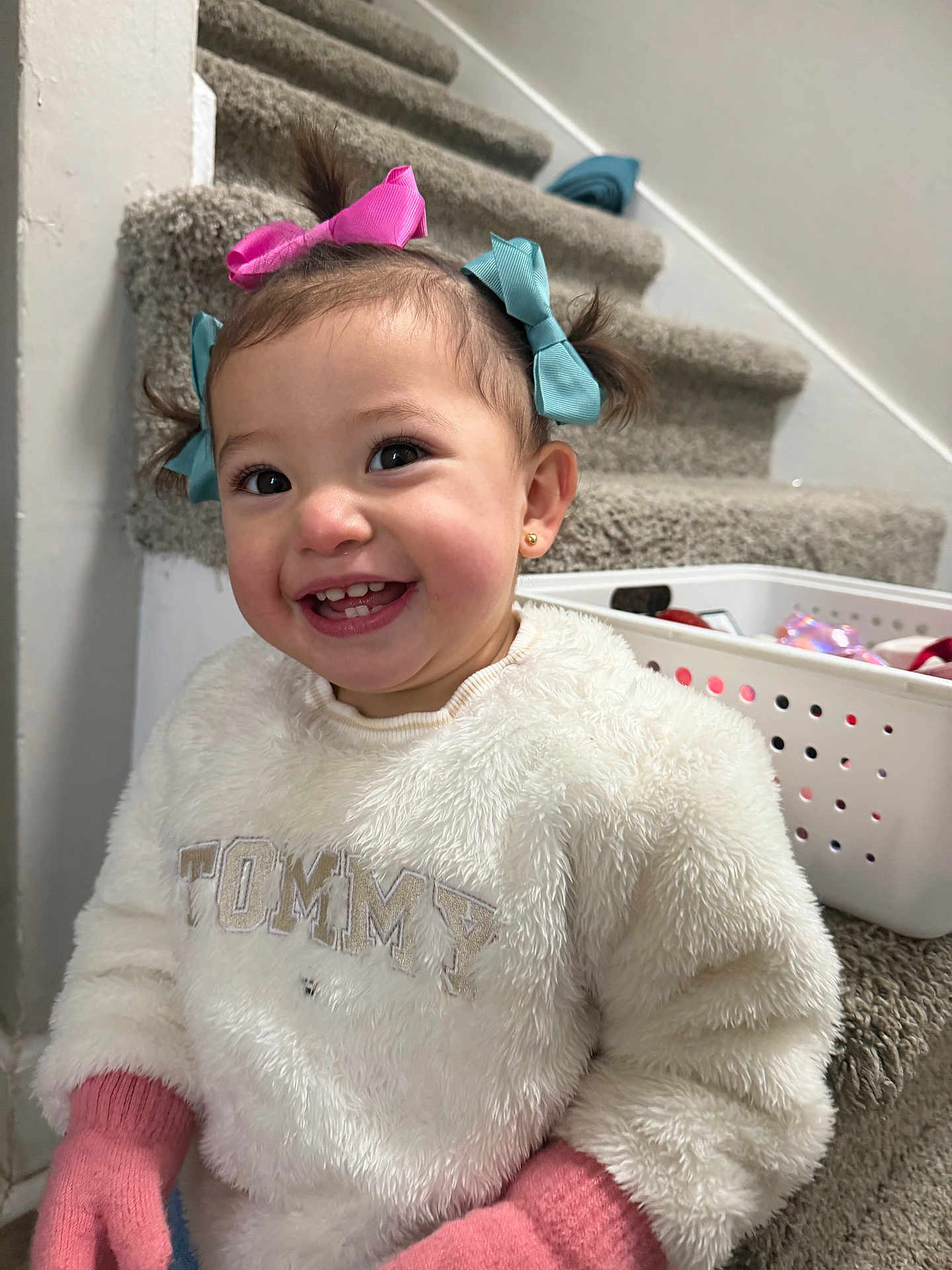 Samara joined the competition — help win amazing prizes! toddler, child, smiling, happy, hair_bows, white_sweater, pink_gloves, carpeted_stairs, basket, indoor, cute, person, portrait, young_child, playful, fashion, home, cozy, clothing, accessories