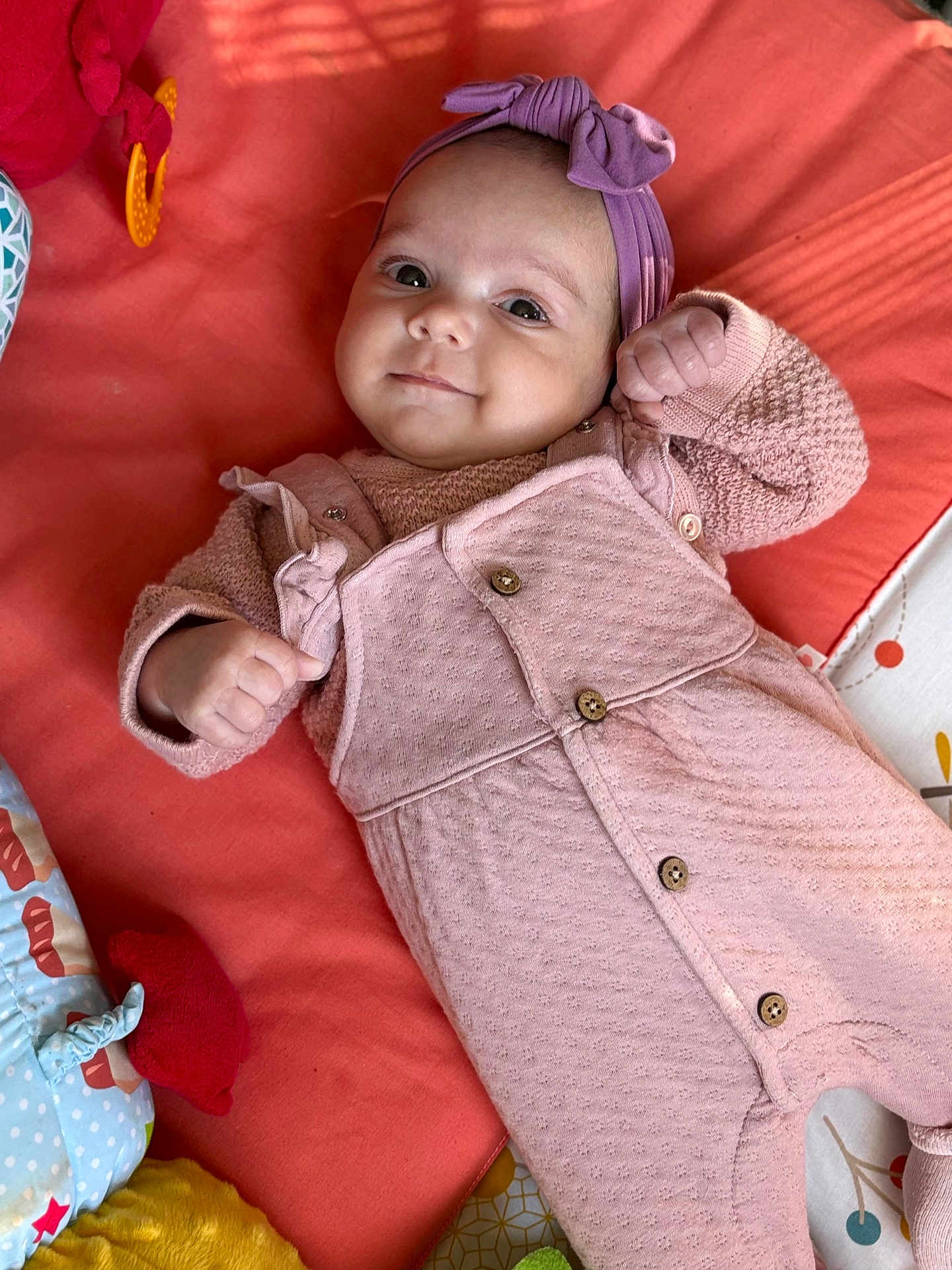 Zoélhya participe au concours pour gagner de l'argent avec cette photo : baby, infant, child, smiling, headband, pink_clothing, blanket, toy, lying_down, cute, portrait, buttoned_overall, purple_bow, indoor, soft_toys, colorful, happy, small_hands, face, cozy